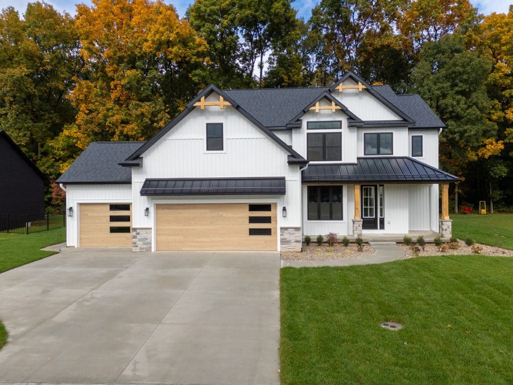 Front of the white modern farmhouse at 2612 Ashford Trail with black trim, cedar gable accents and a wood-look three-car garage.