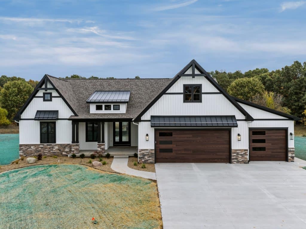 Front of the white farmhouse-style ranch at 8050 W PQ Ave with stone accents and a three-car garage.