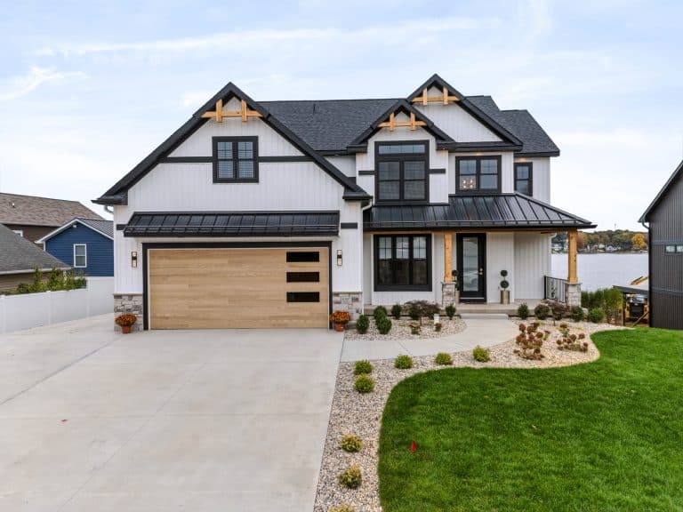 Front of the white modern farmhouse at 8107 W PQ Ave with black trim, cedar gable accents and a wood-look garage door.